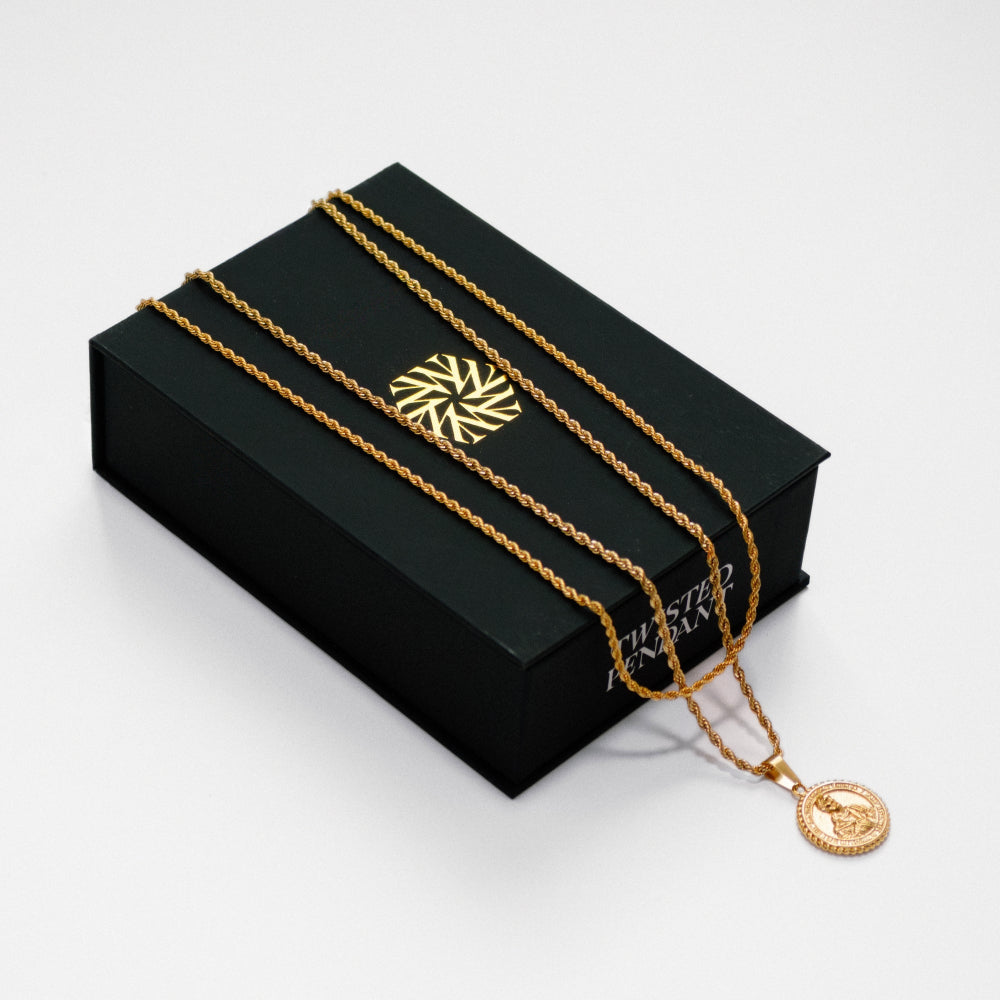 Gold necklace with a pendant on a black box against a white background