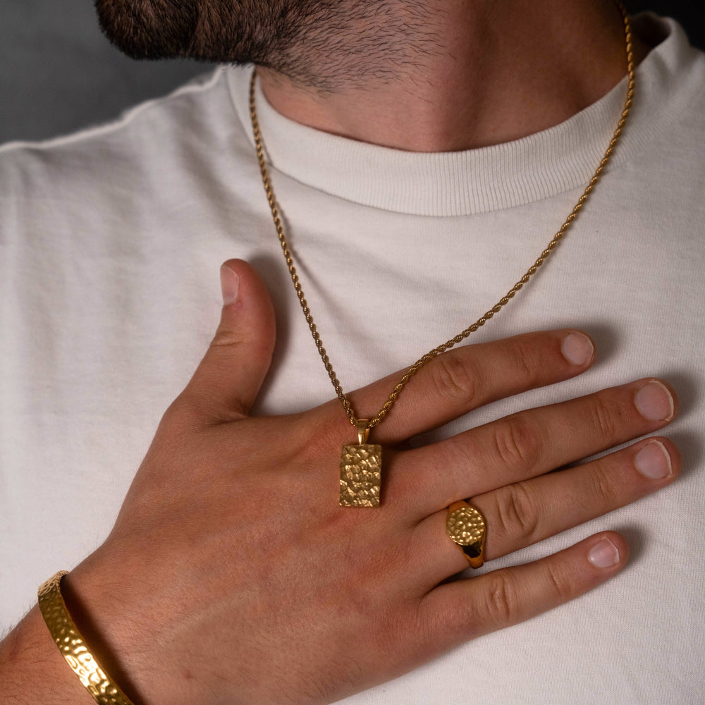 Gold necklace and ring on a person wearing a white shirt
