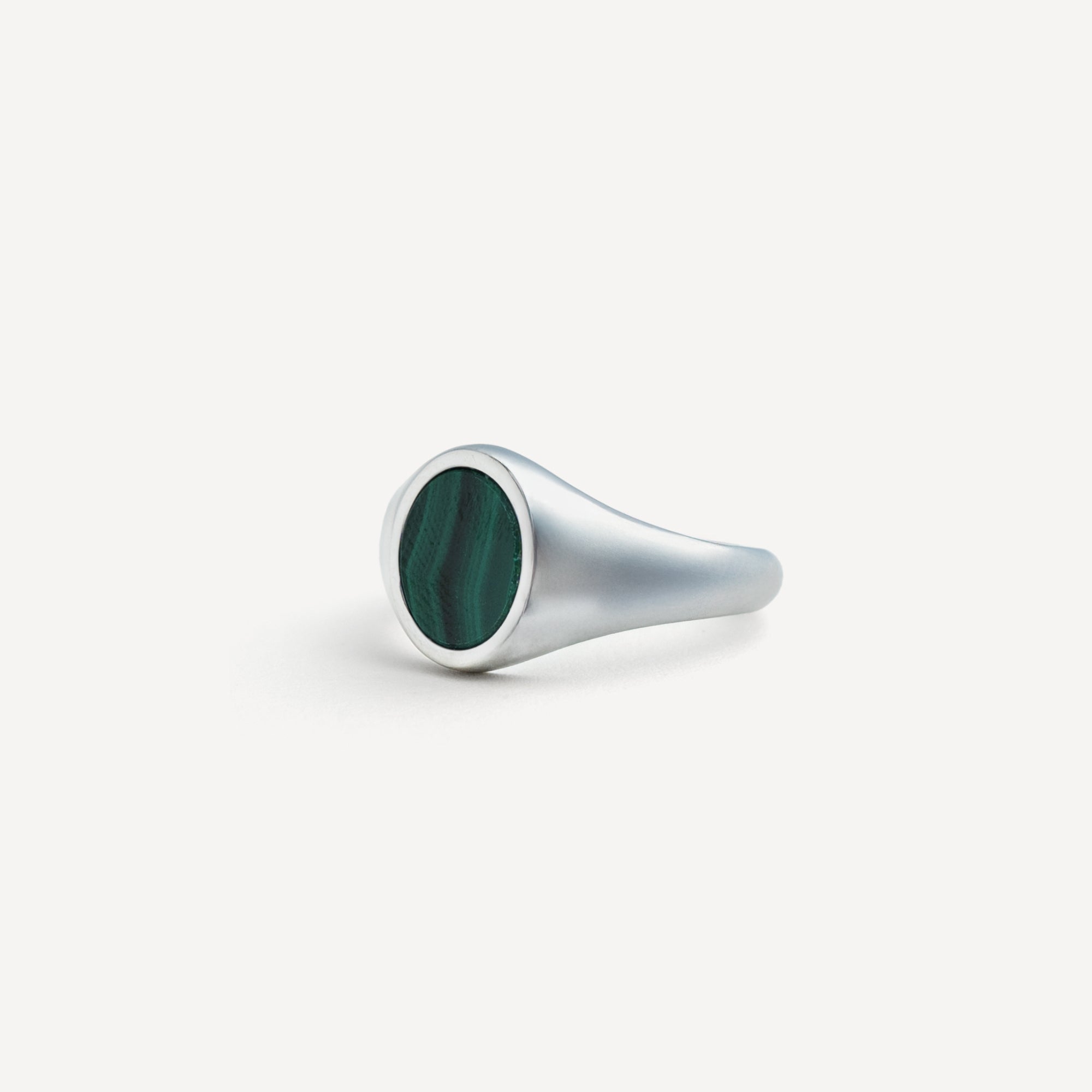 Silver ring with a green gemstone on a white background