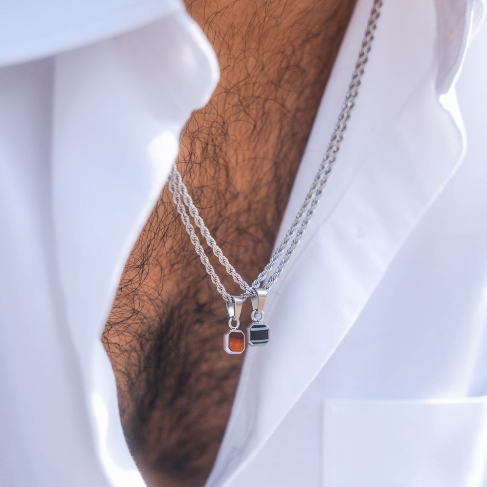 Two silver necklaces with gemstone pendants on a white shirt background