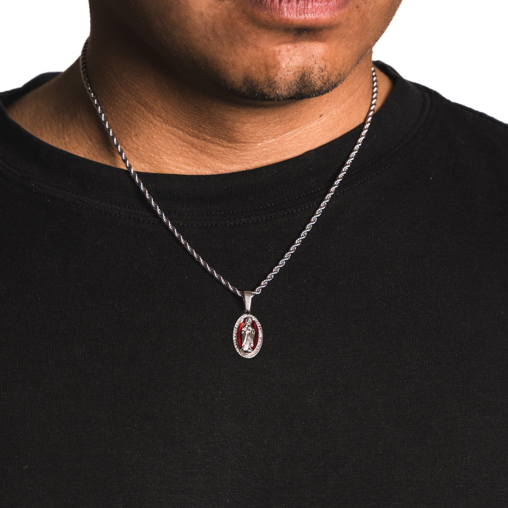 Person wearing a black shirt with a silver necklace featuring a pendant.