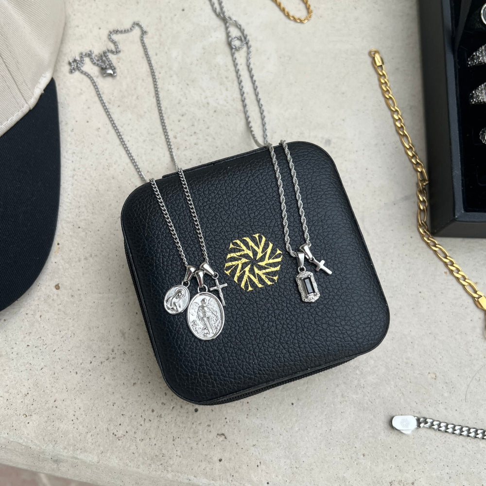 Black jewelry case with necklaces featuring various pendants on a light surface.