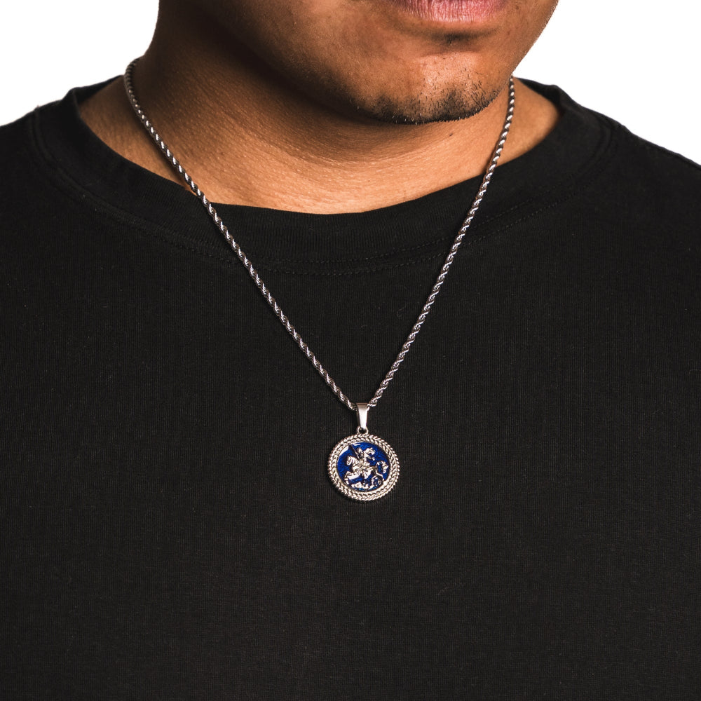 Man wearing a black shirt with a silver necklace featuring a round pendant.