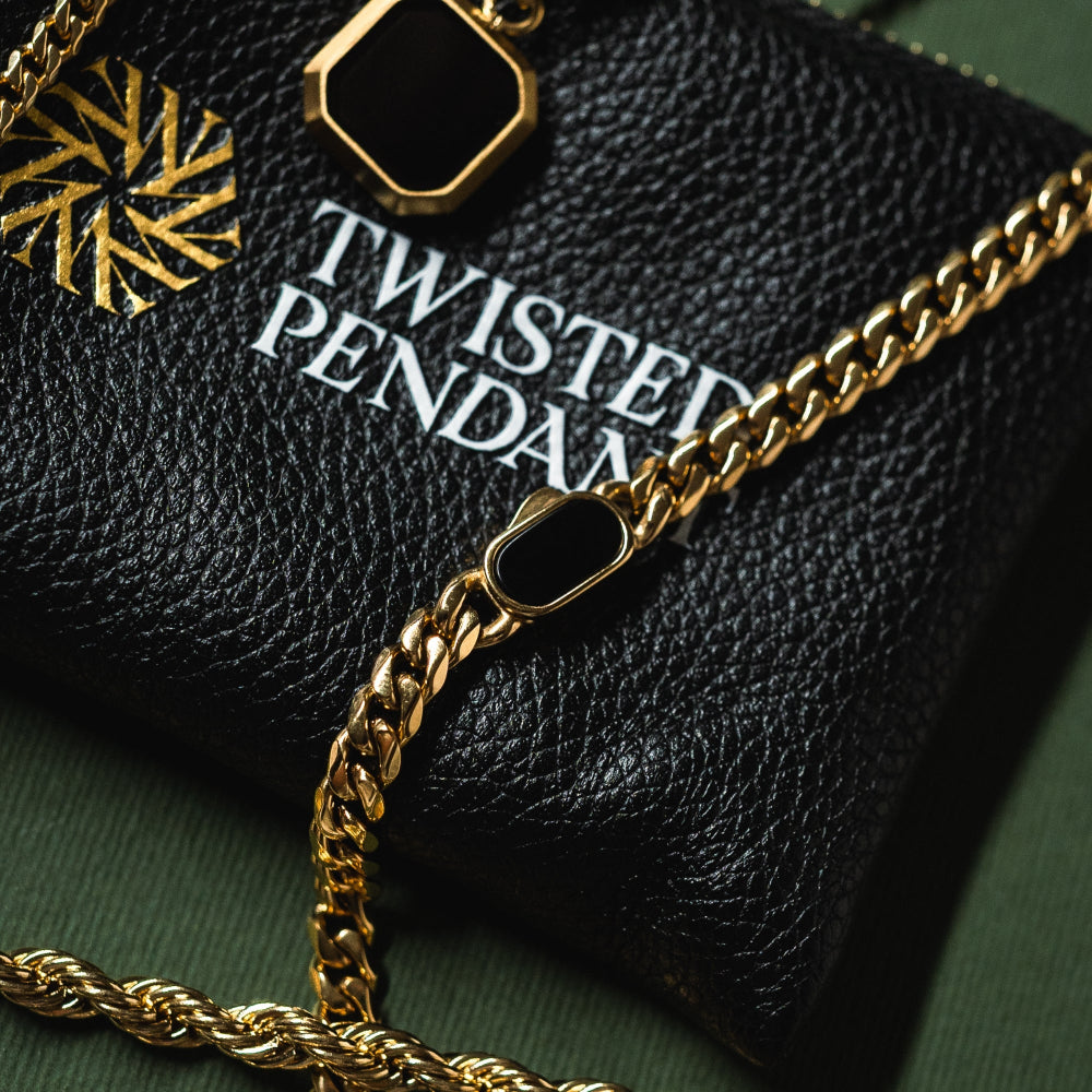 Gold chain necklace on a black textured surface with 'Twisted Pendan' branding.