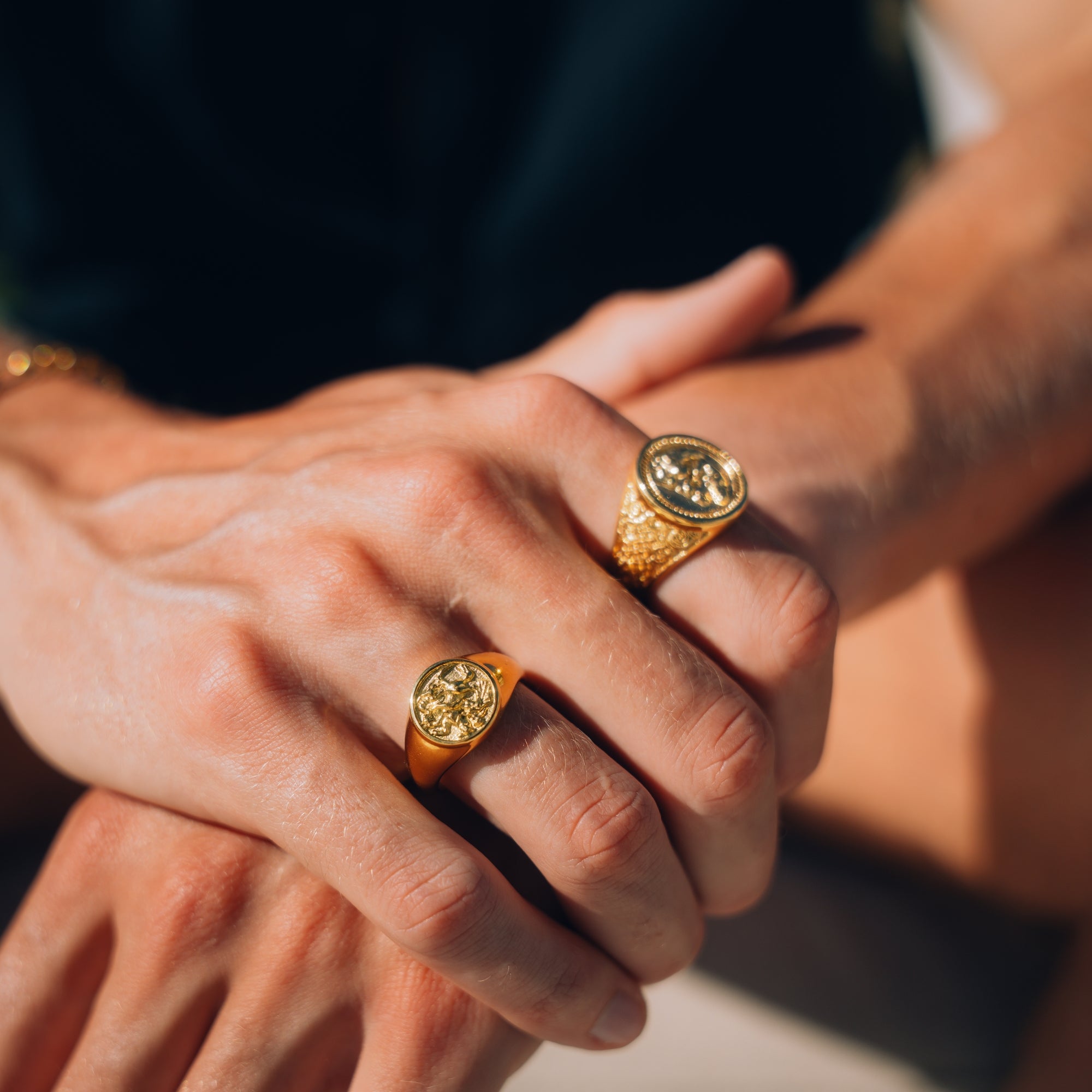 Close-up of hands wearing gold rings with sunlit background