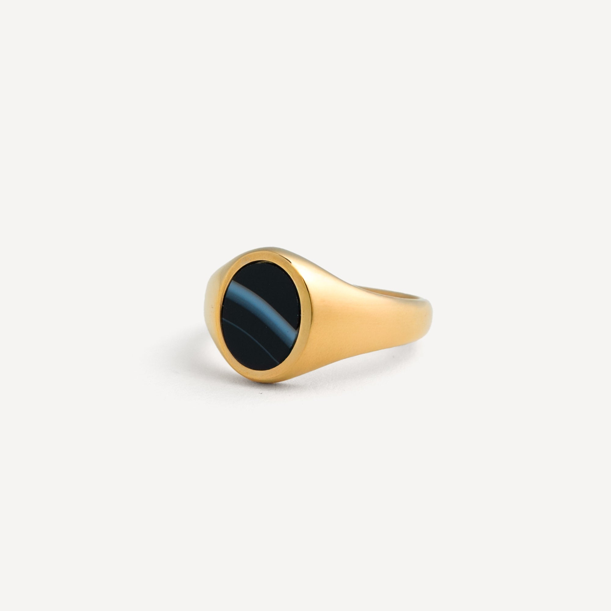 Gold ring with a black stone on a white background