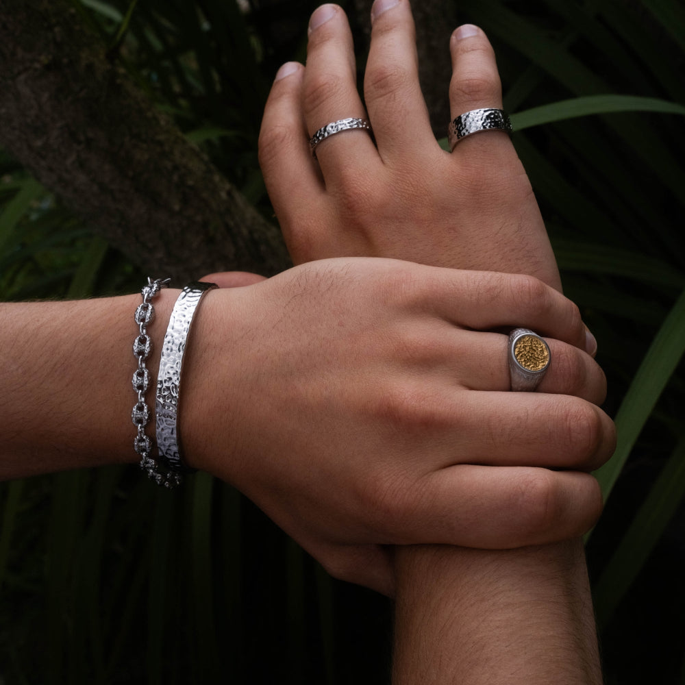 Close-up of hands with silver rings and bracelets against a dark background