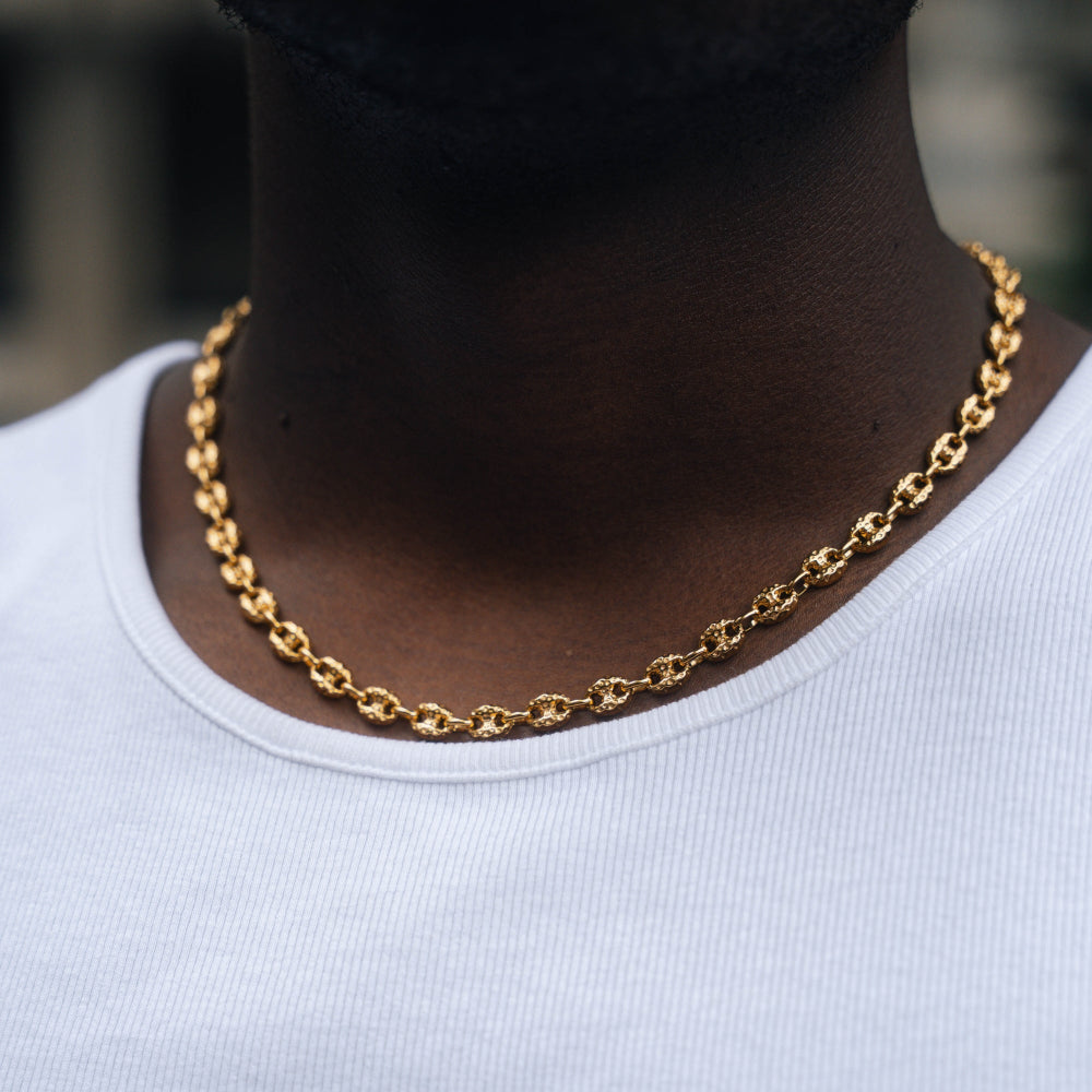 Gold chain necklace worn by a person with a blurred background