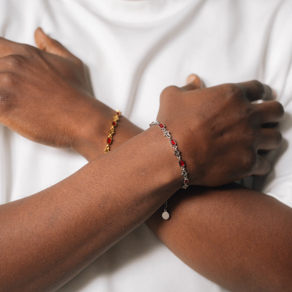 Close-up of two hands wearing red beaded bracelets on a white background