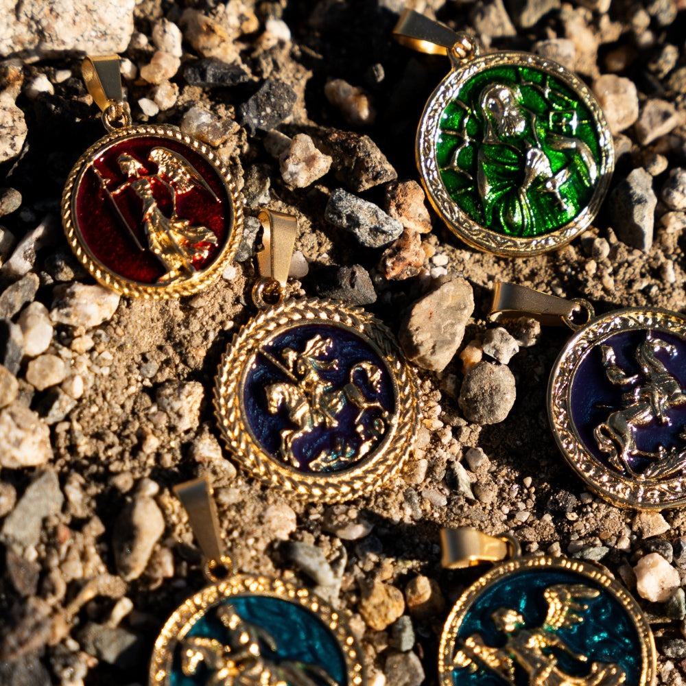 Gold pendants with colorful enameled designs on a rocky surface