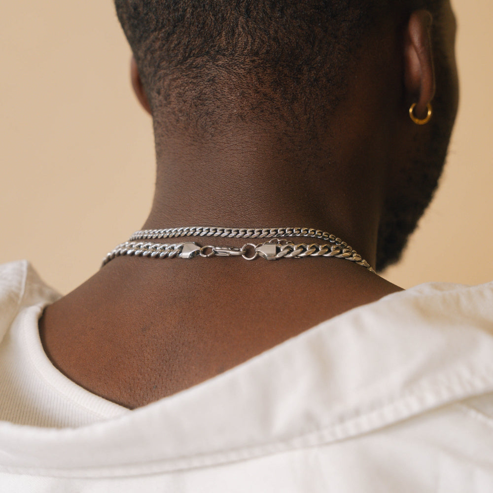 Person wearing multiple necklaces with a neutral background