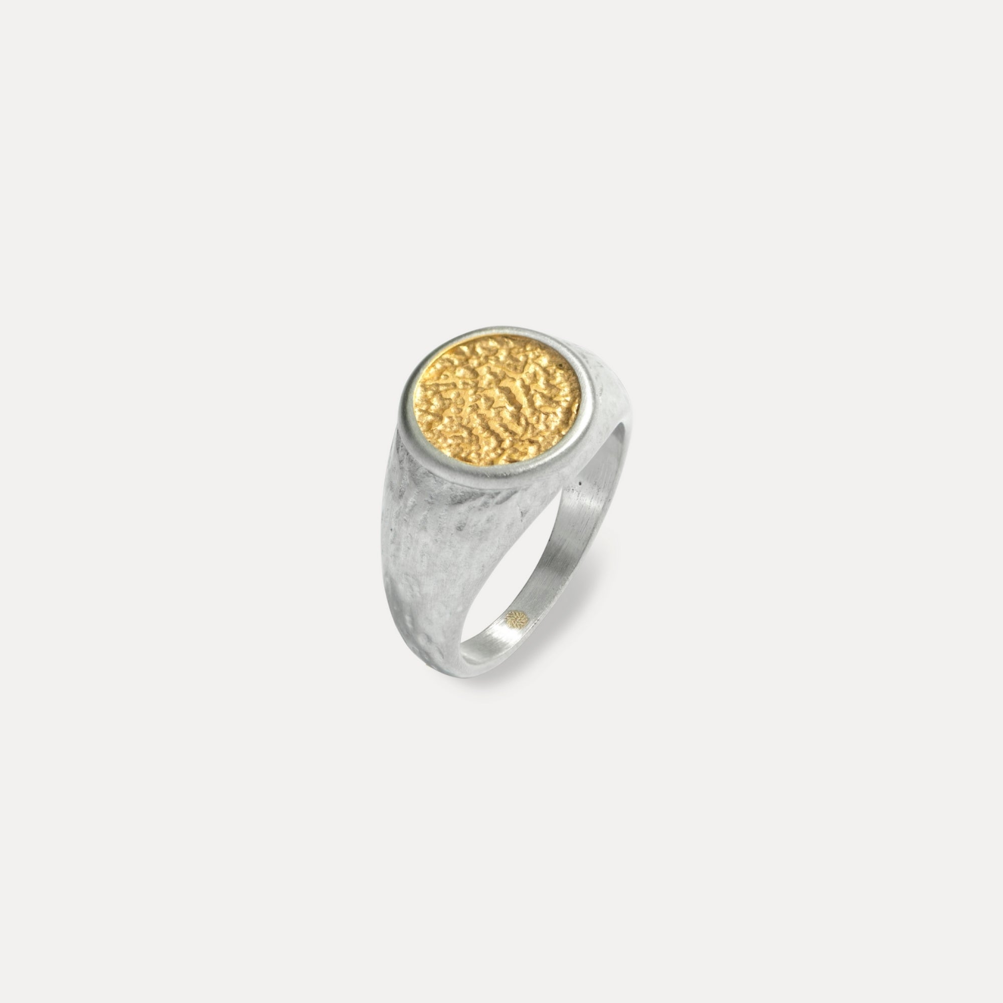 Silver ring with a gold circular inset on a light gray background