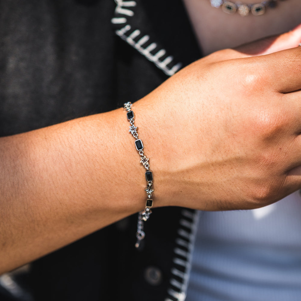 Close-up of a person's wrist wearing a silver bracelet with black stones.
