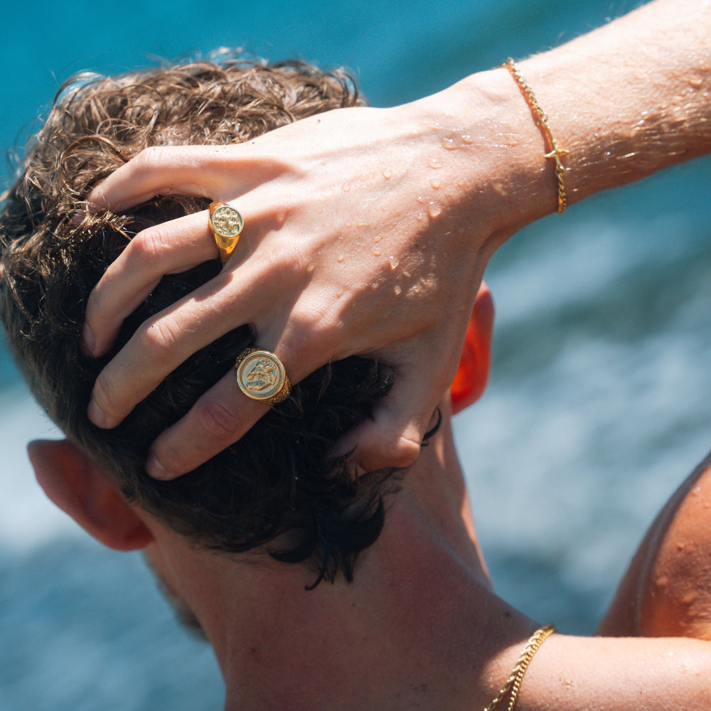 Person with gold rings and bracelets against a blurred blue background