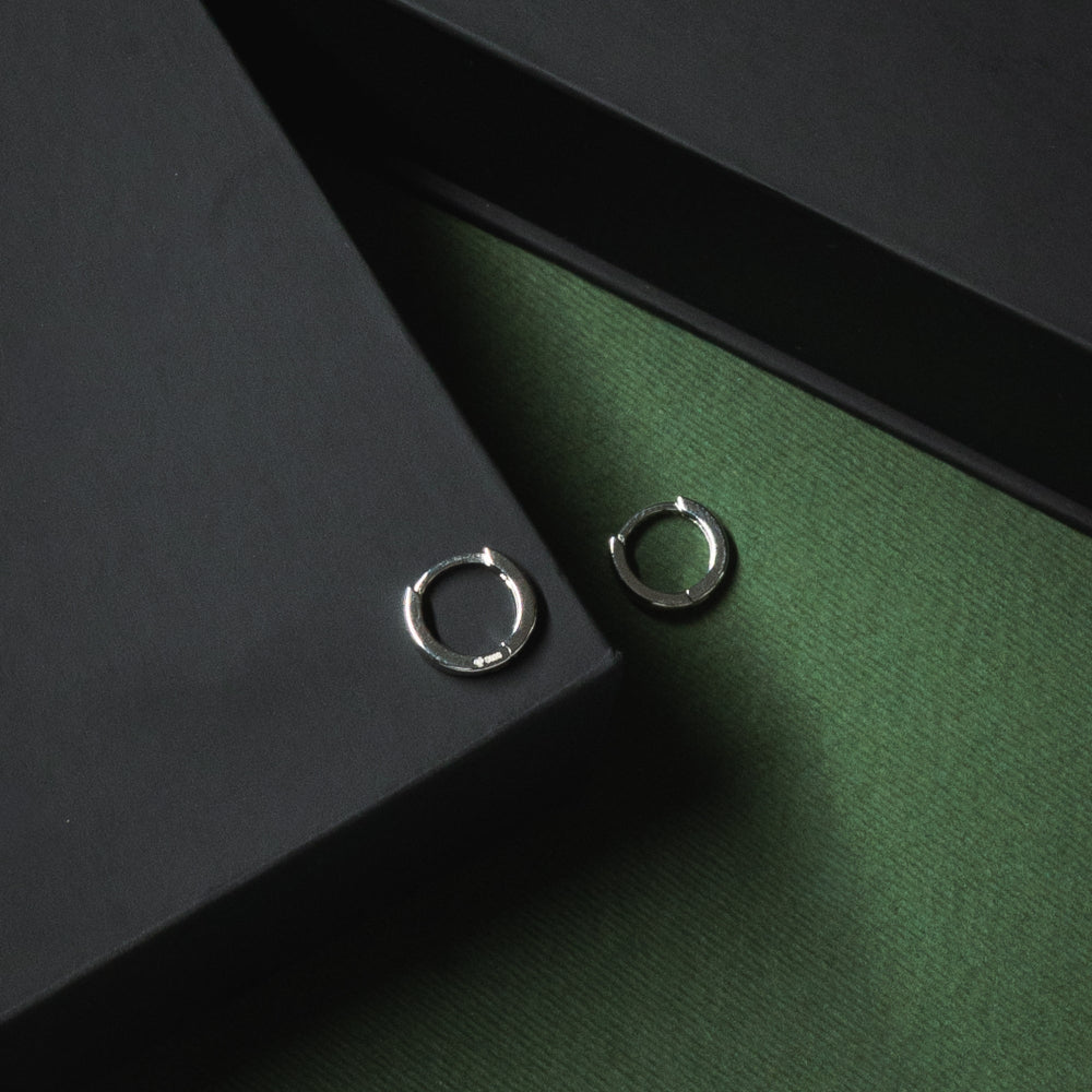Two silver rings on a dark green surface with a black background