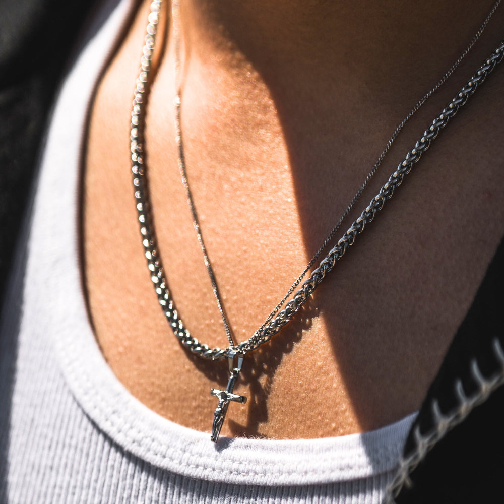 Close-up of layered necklaces on a person wearing a gray top.