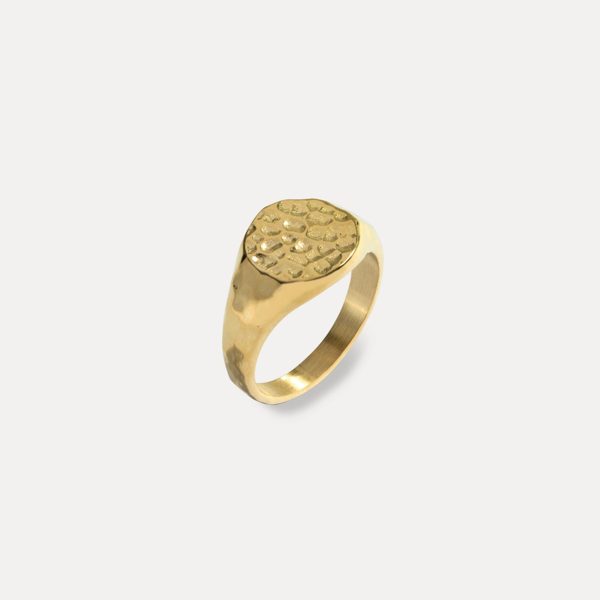 Gold ring with textured design on a light gray background