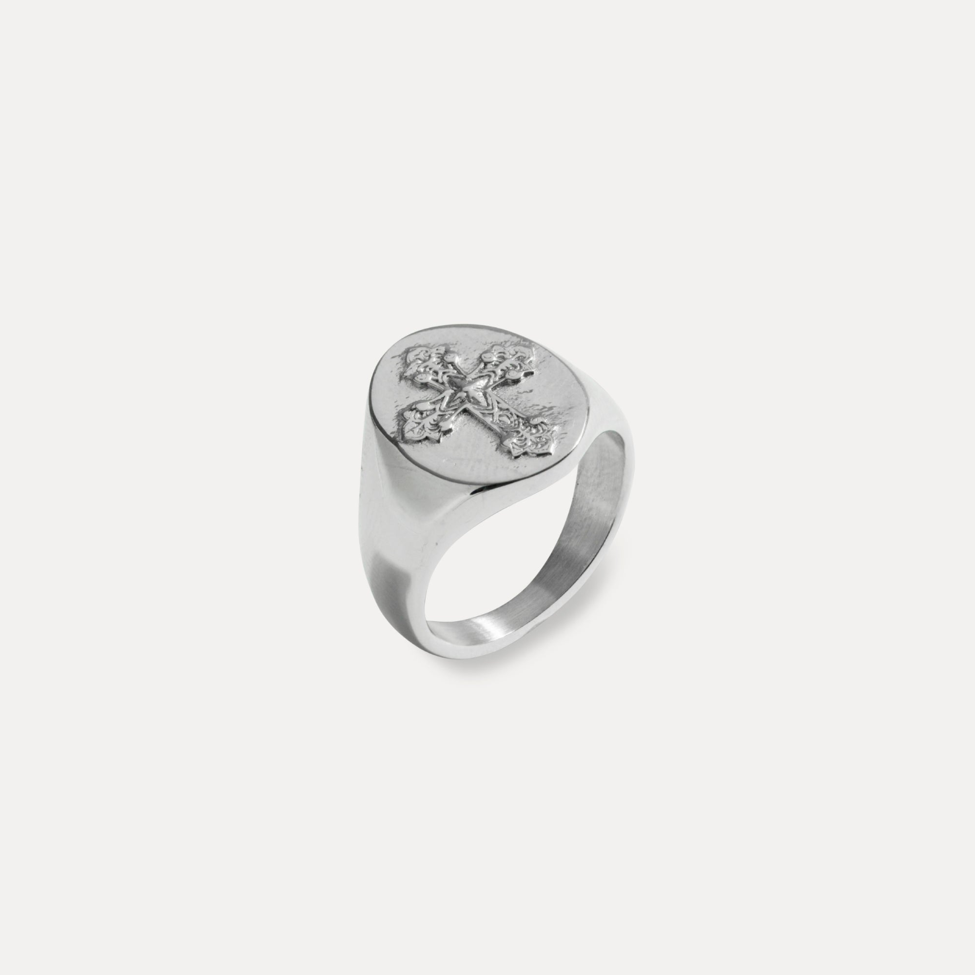 Silver ring with a cross design on a light gray background