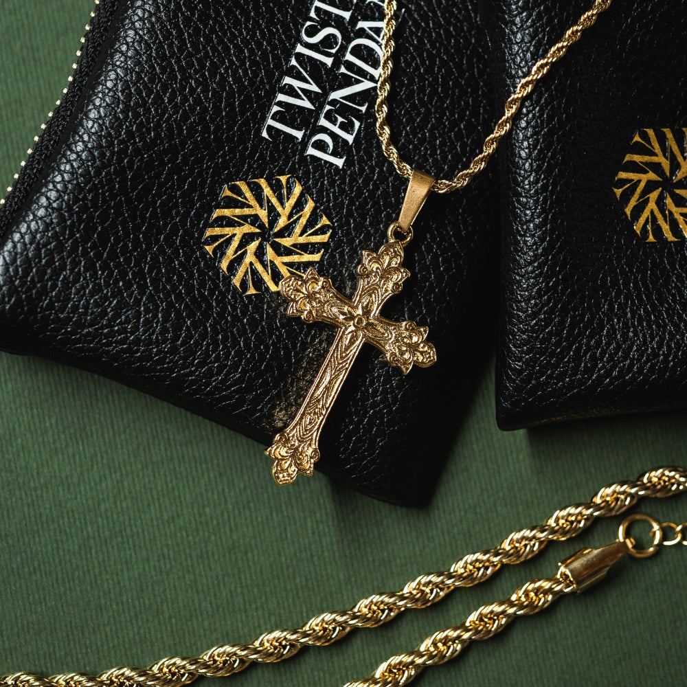 Gold cross necklace on a black leather case with 'Twist' branding.