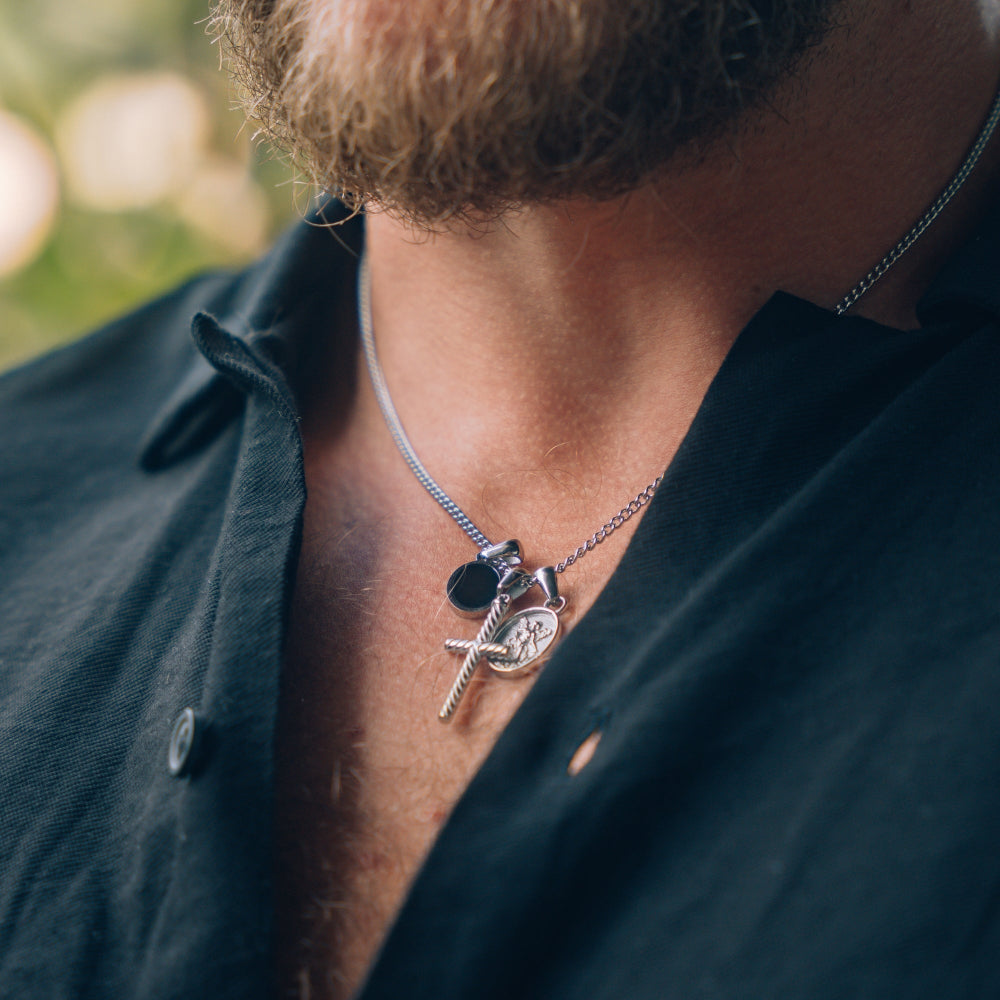 Close-up of a person wearing a necklace with multiple pendants outdoors