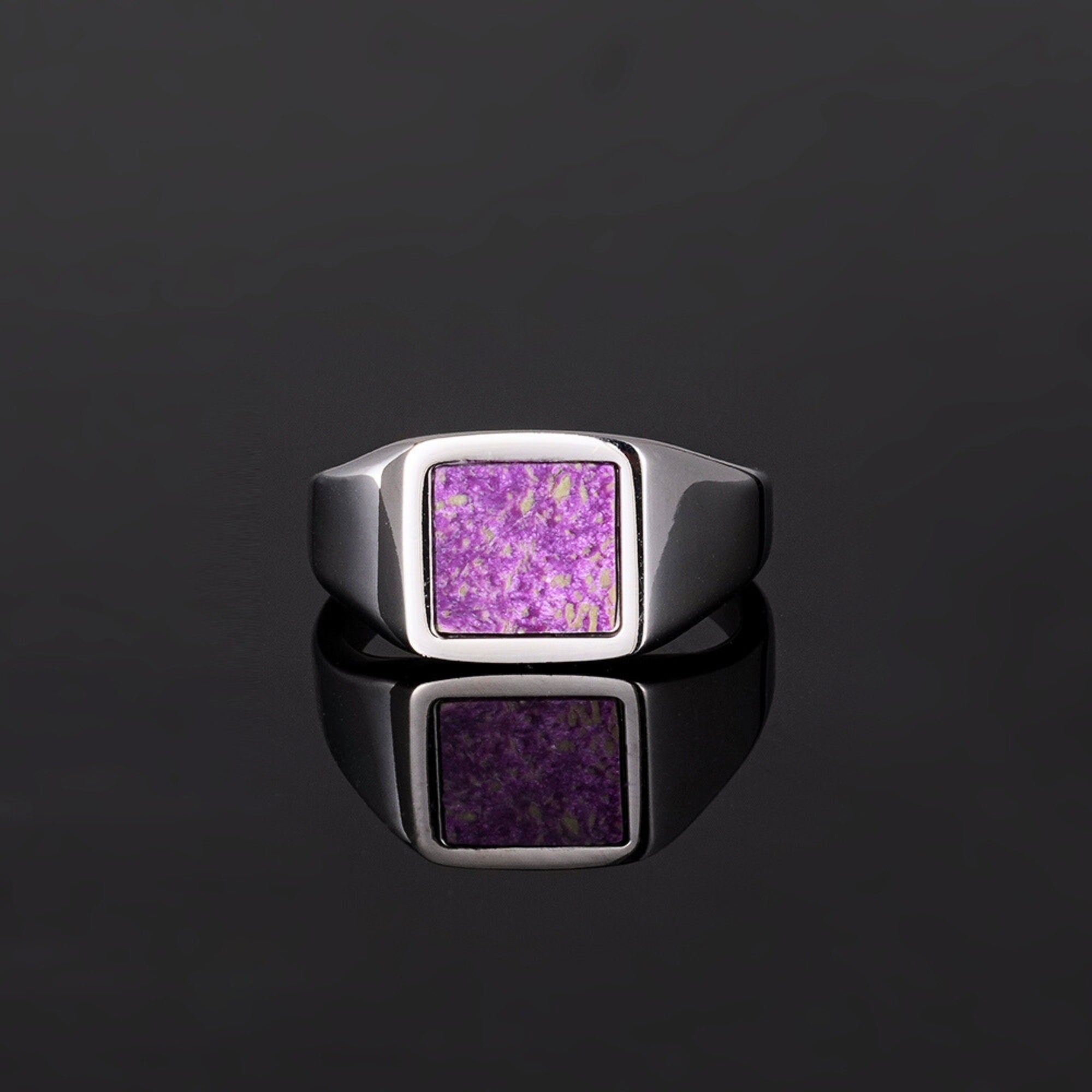 Silver ring with a purple square stone on a black background