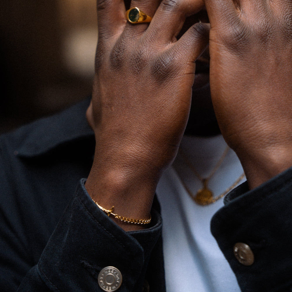 Close-up of hands with gold jewelry against a blurred background