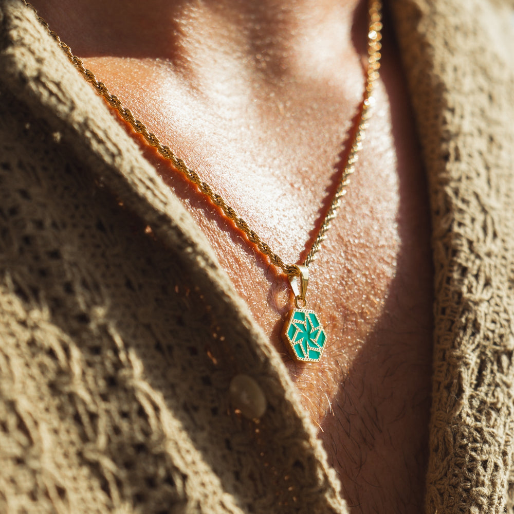 Necklace with a green pendant on a person wearing a textured garment.