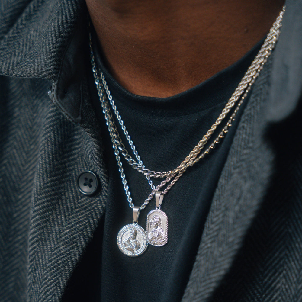 Two necklaces with pendants on a person wearing a dark shirt and gray jacket.