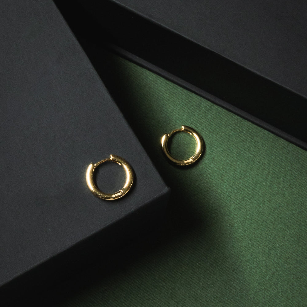 Gold hoop earrings on a dark green and black background