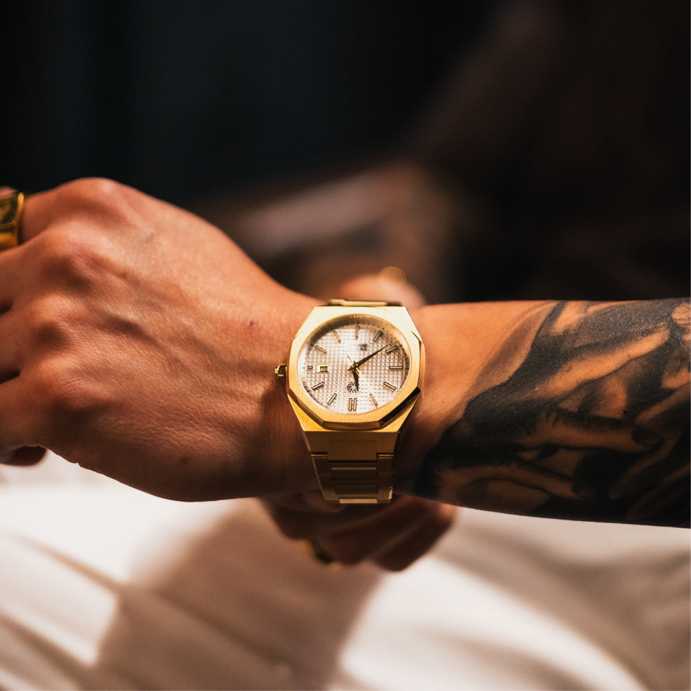 Gold wristwatch on a person's wrist with a blurred background