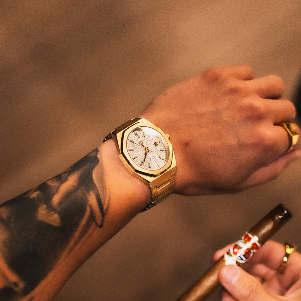 Gold wristwatch on a wrist with tattoos and a blurred background