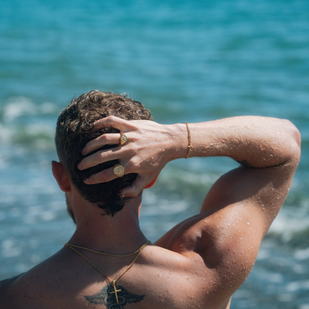 Person with a tattoo on their shoulder against a blue ocean background