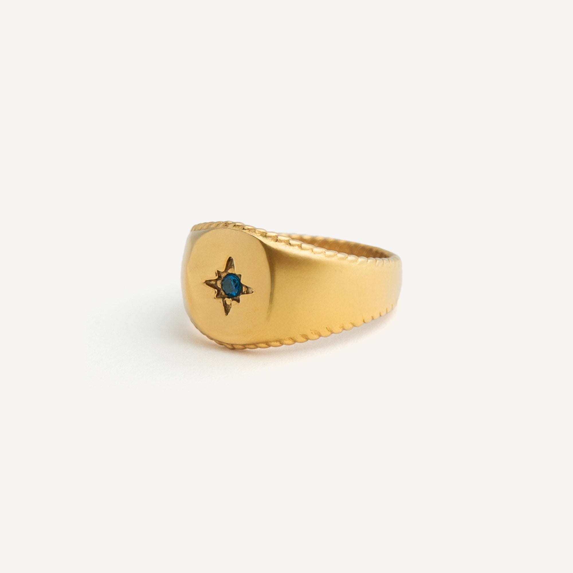 Gold ring with a blue gemstone on a white background