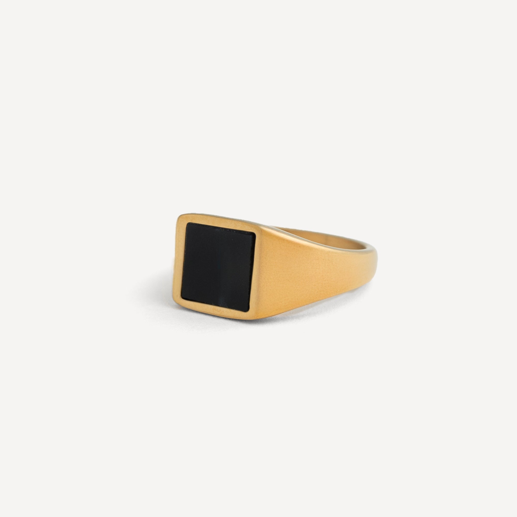 Gold ring with a black stone on a white background