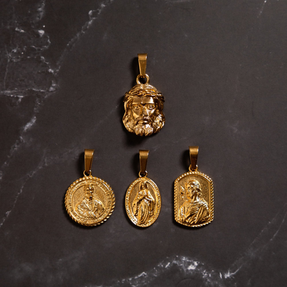 Four gold pendants with different designs on a dark marble surface
