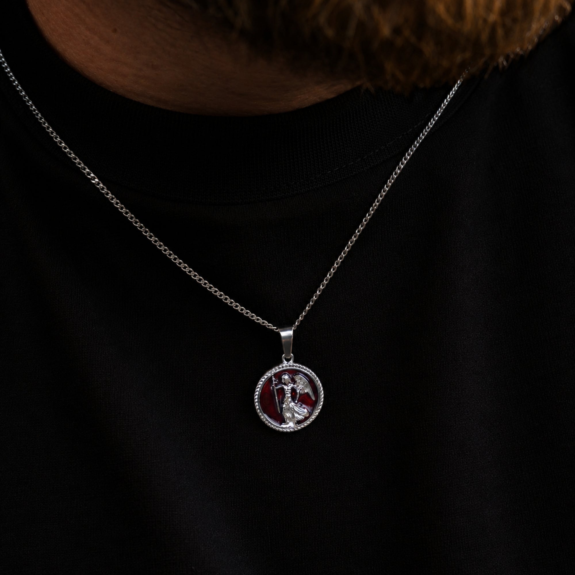 Silver necklace with a circular pendant on a black background