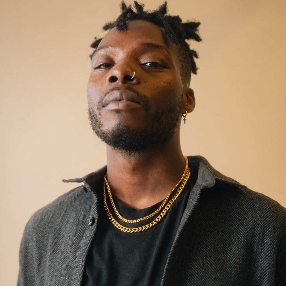 Man wearing a gold chain necklace against a beige background