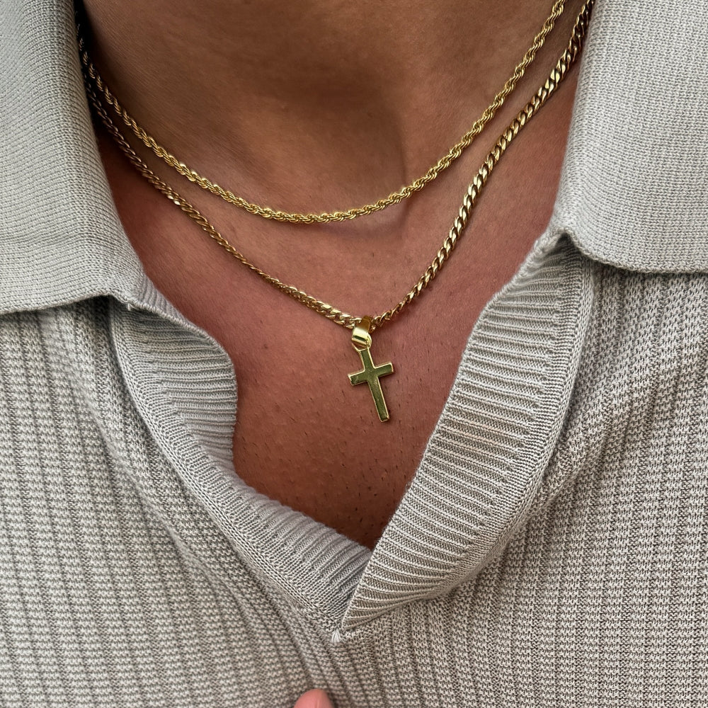 Gold necklace with a cross pendant worn by a person in a gray shirt.