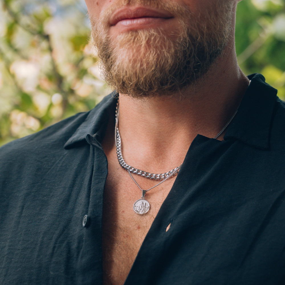 Man wearing a black shirt with a silver chain necklace outdoors