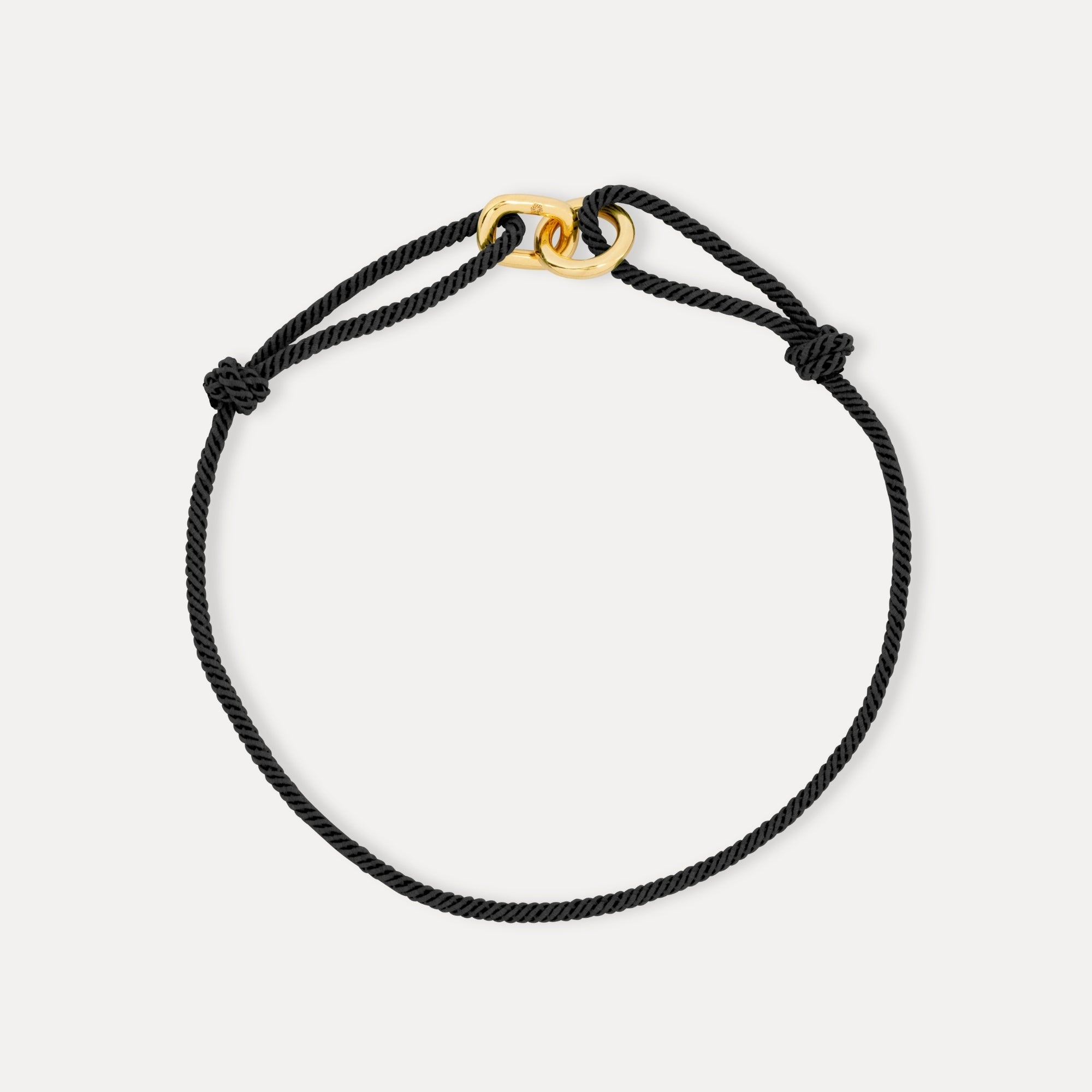 Black cord bracelet with a gold clasp on a white background