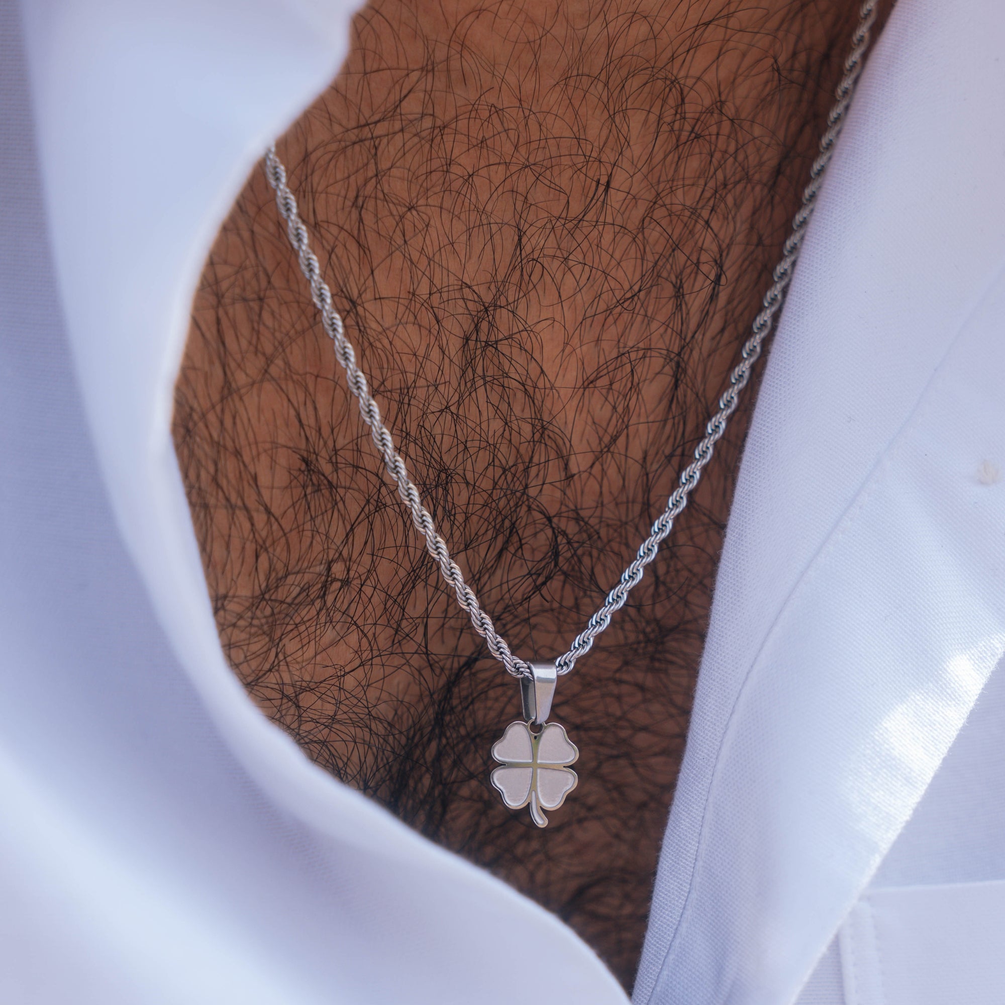 Silver necklace with a clover pendant on a mannequin bust.