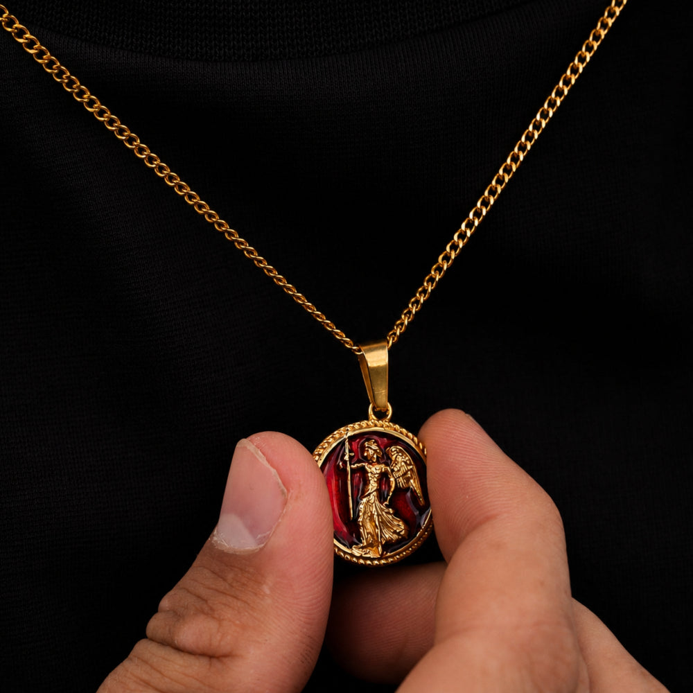 Gold necklace with a detailed pendant held by a hand against a black background