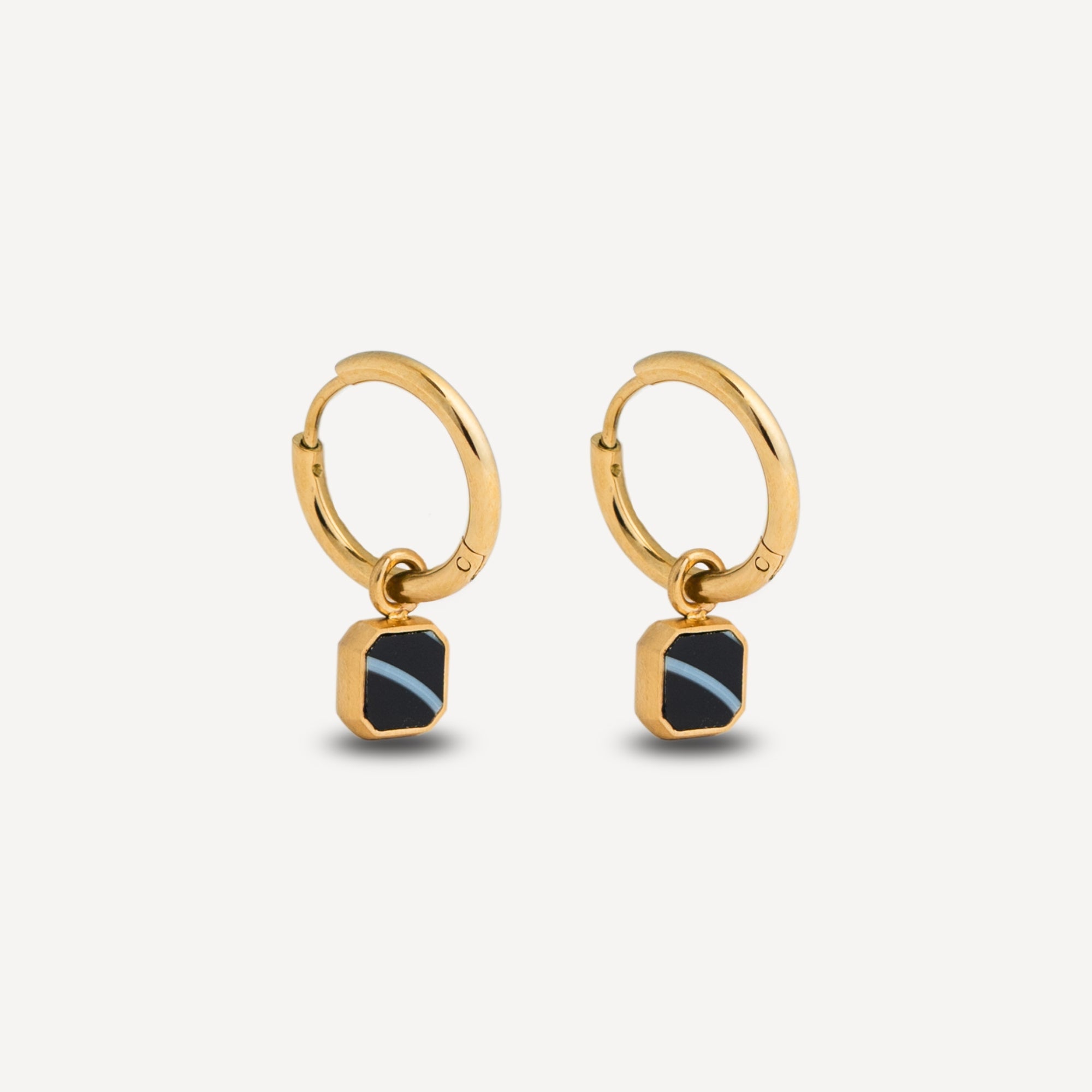 Gold hoop earrings with black stone drops on a light gray background