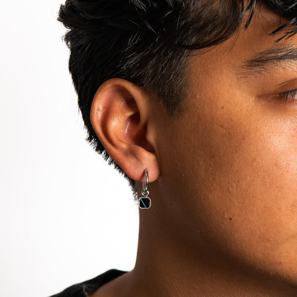 Close-up of an ear wearing a dangling earring with a clear background