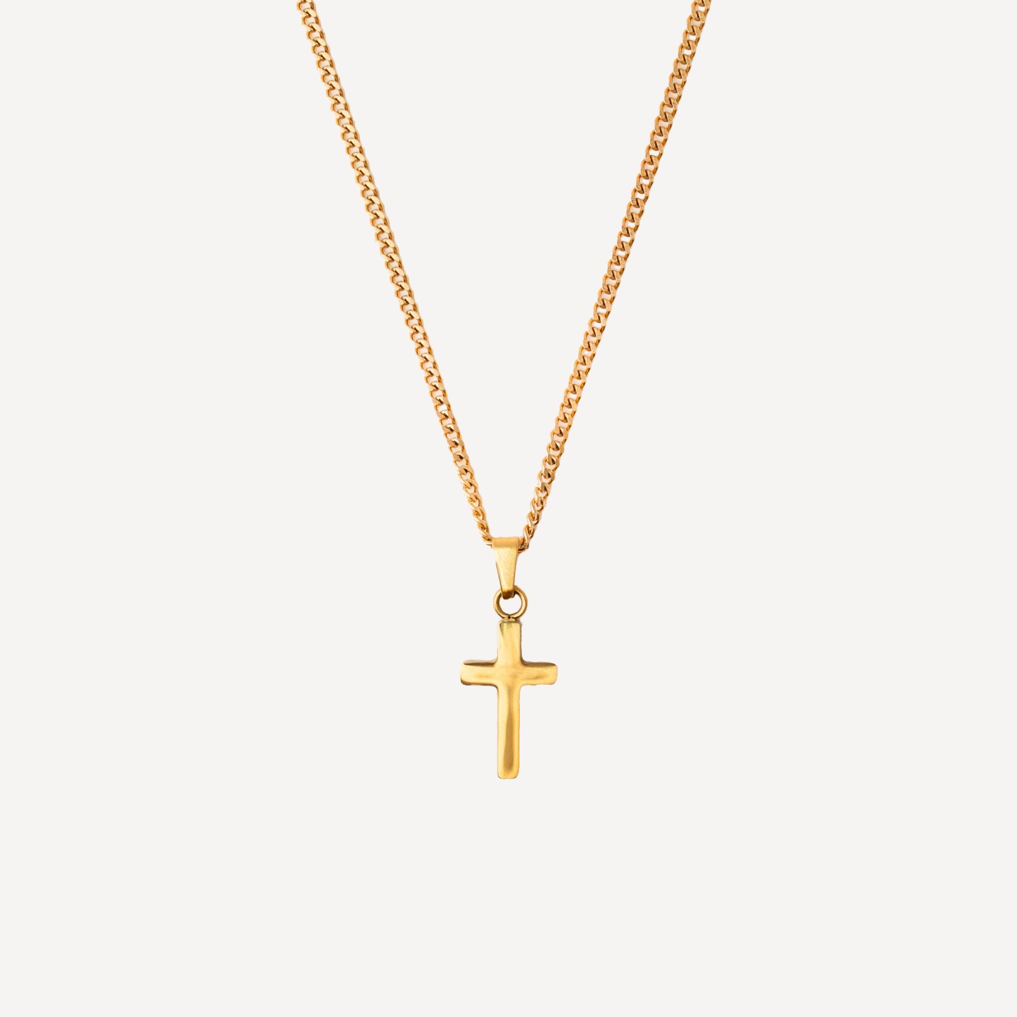 A gold cross pendant necklace on a gold curb chain, shown against a light gray background.