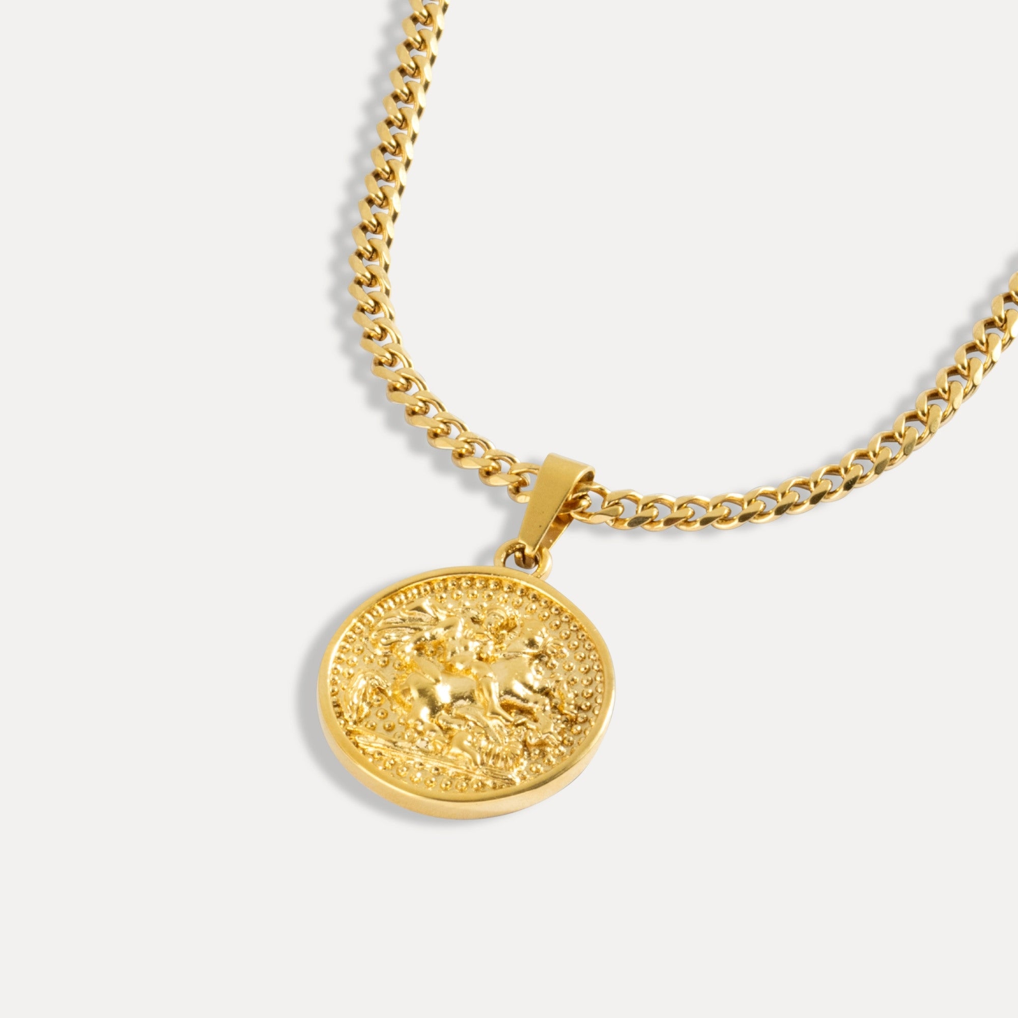 Gold necklace with a round pendant on a light gray background