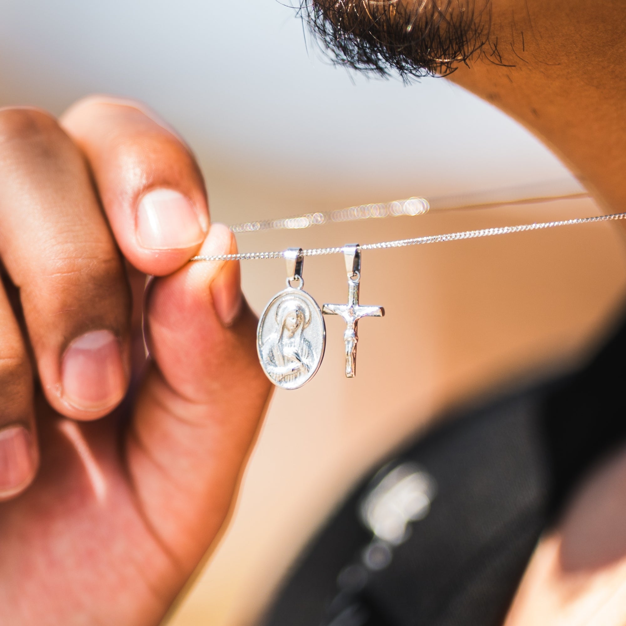 Close-up of a hand holding a silver necklace with two pendants.
