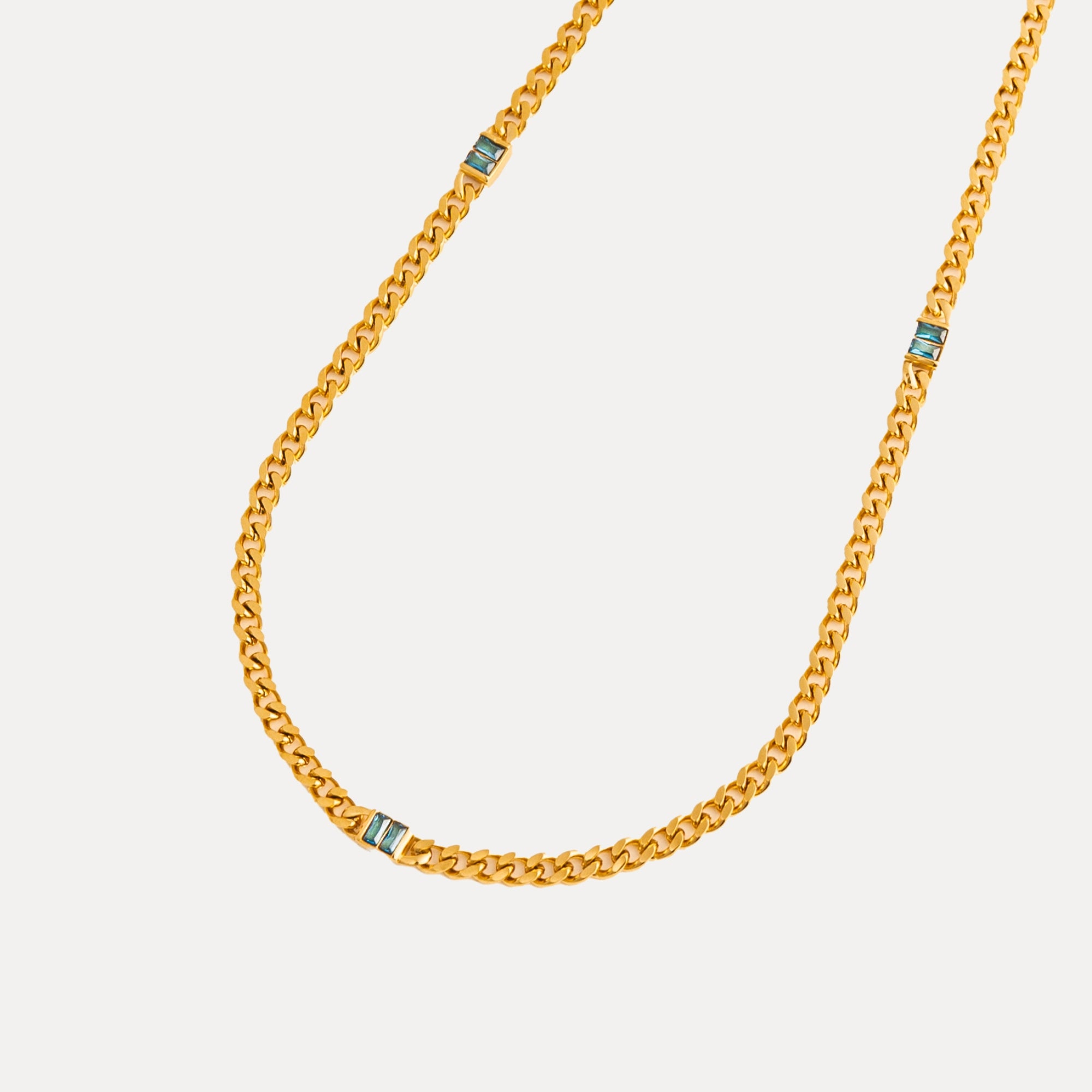 Gold chain necklace with blue accents on a white background