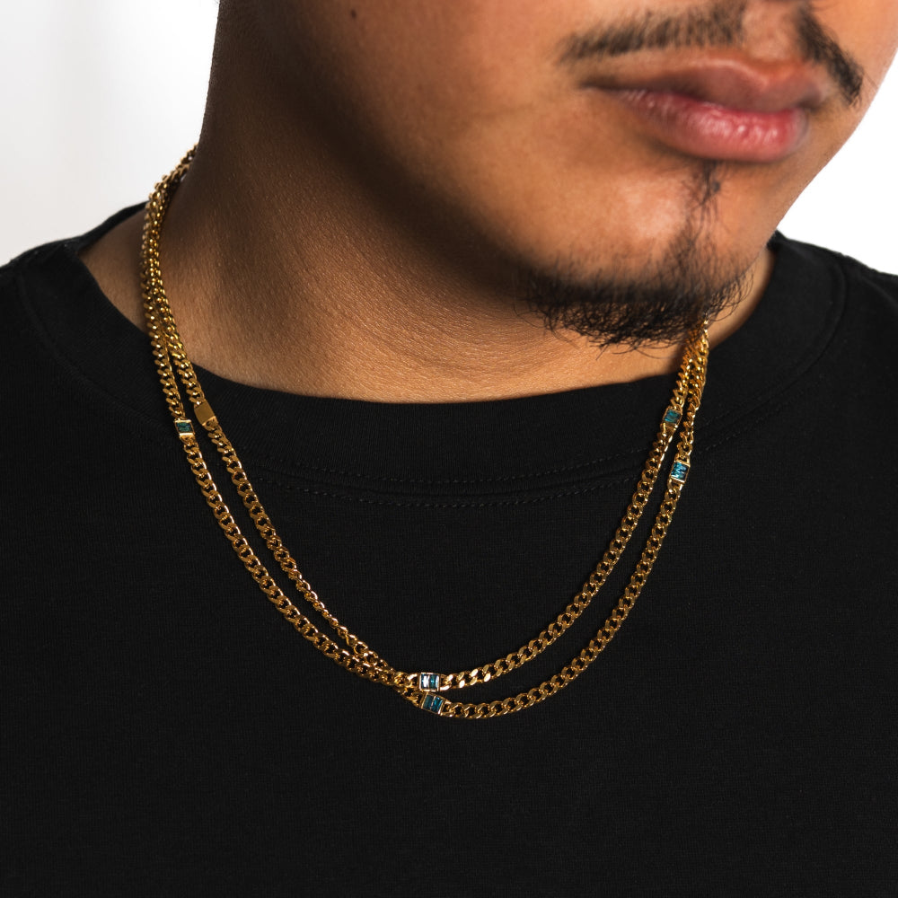 Man wearing a gold chain necklace on a plain background
