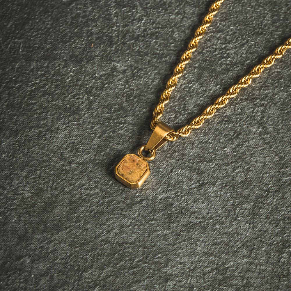 Gold necklace with a pendant on a dark gray background